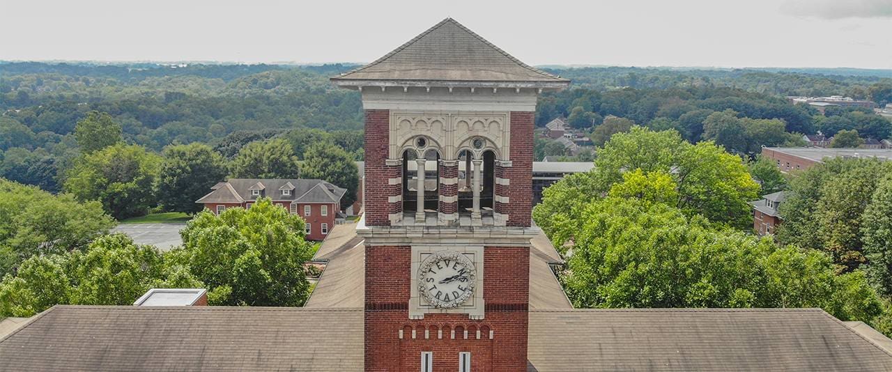 Mellor Building Tower and Stevens Trades Clock with trees and blue sky in the background