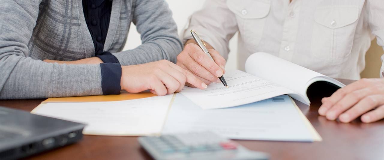 Two people work on filling out a form. 