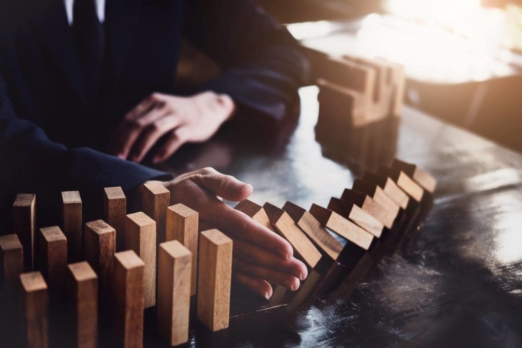 A hand stopping the fall of dominoes. 