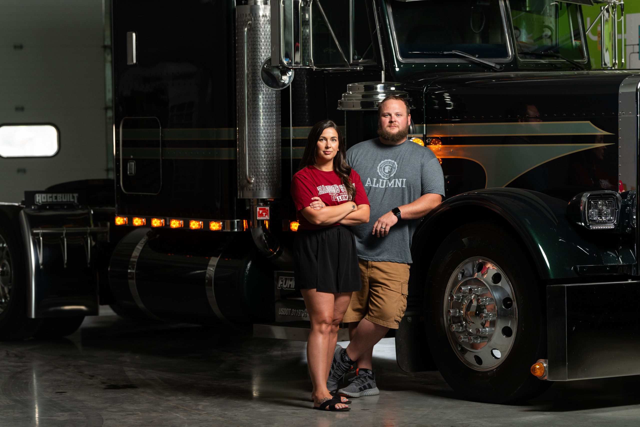 Two graduates of Thaddeus Stevens College of Technology stand next to a diesel truck they owned at their business. 