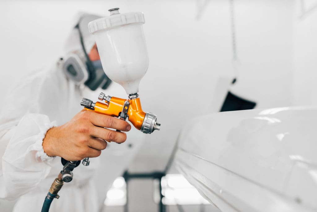 White car being painted with paint gun 