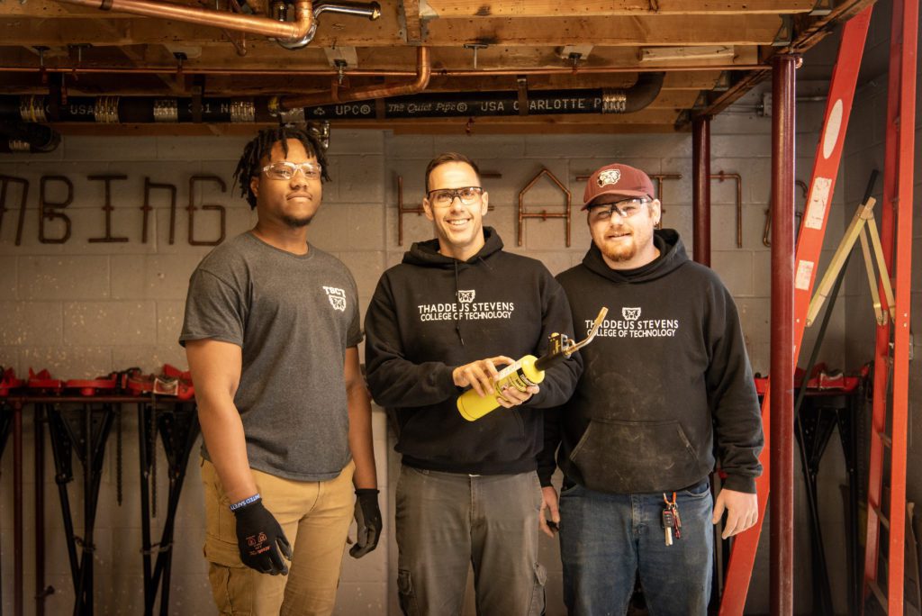 Two plumbing students and a faculty member in the plumbing lab at Thaddeus Stevens College.