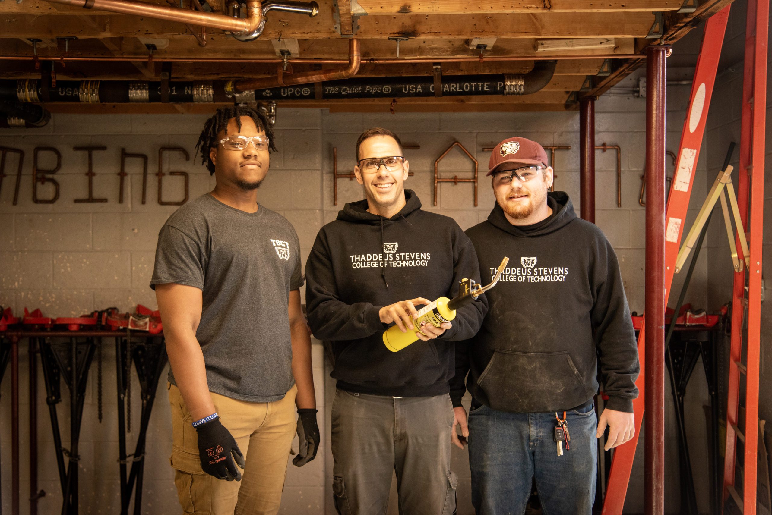 Two plumbing students and a faculty member in the plumbing lab at Thaddeus Stevens College. 