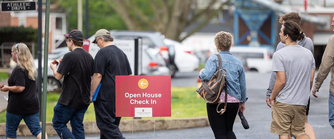 Thaddeus Stevens College Open House Check In Sign with visitors and students walking in the background on campus
