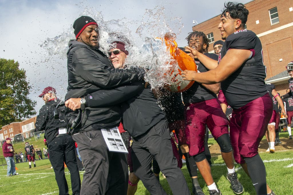 Coaches and student athletes celebrate after a football game. 