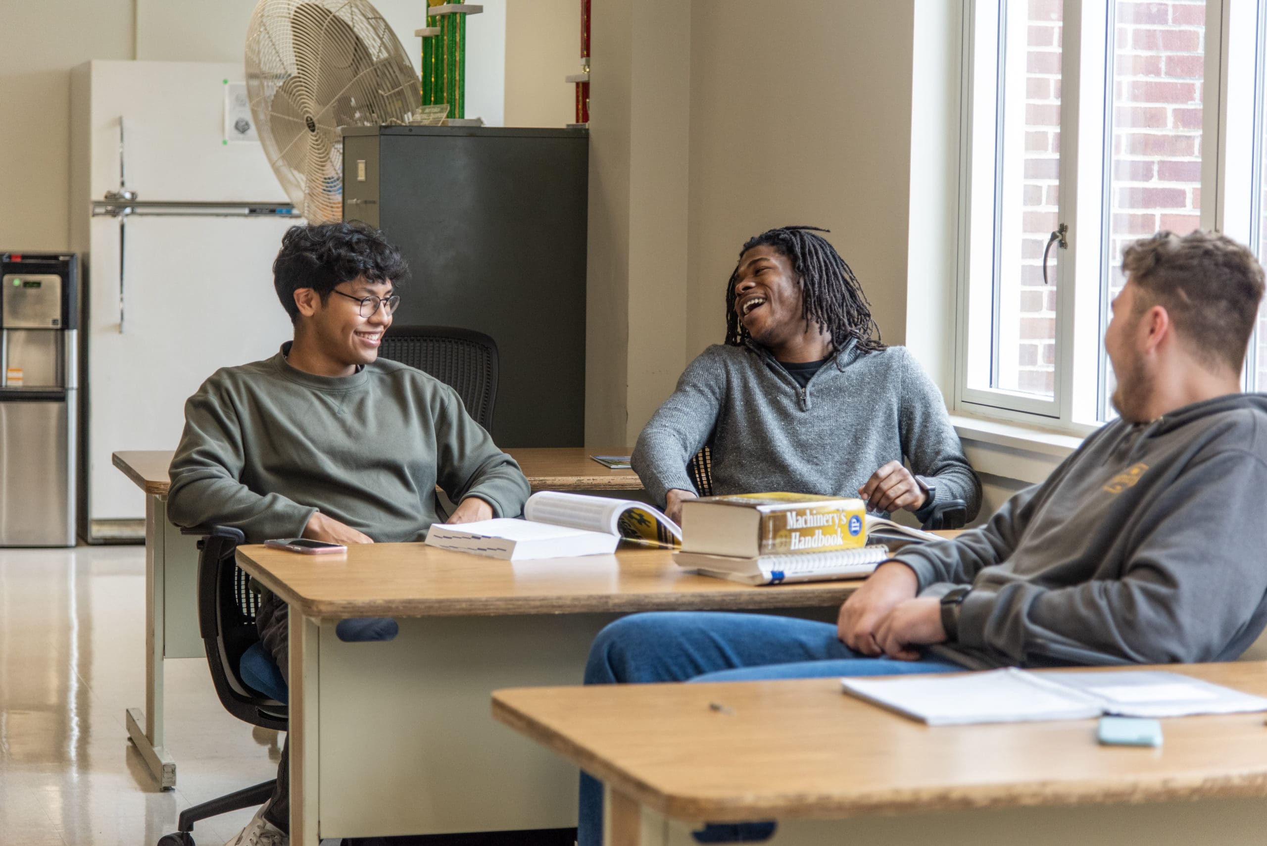 3 Thaddeus Stevens College of Technology students laughing in the classroom. 