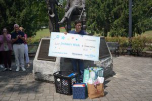 Joshua holding the Make A Wish check in front of the Thaddeus Stevens statue